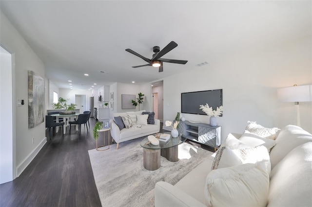 living room with ceiling fan and dark wood-type flooring