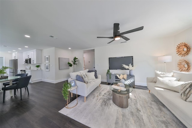 living room with ceiling fan and dark wood-type flooring