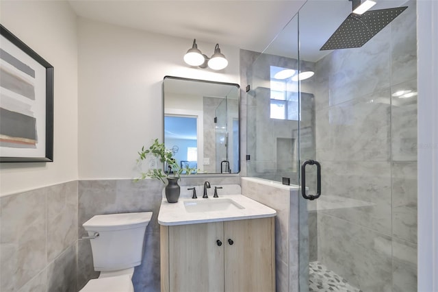 bathroom with vanity, toilet, a shower with door, and tile walls