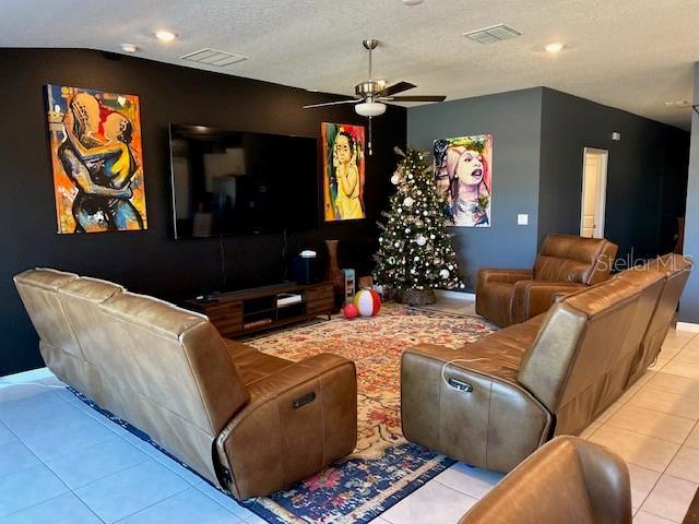 home theater room with light tile patterned floors, a textured ceiling, ceiling fan, and lofted ceiling