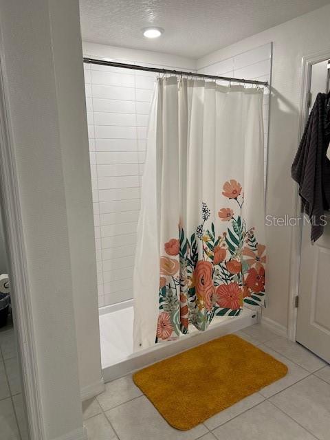 bathroom featuring tile patterned floors, a shower with curtain, and a textured ceiling