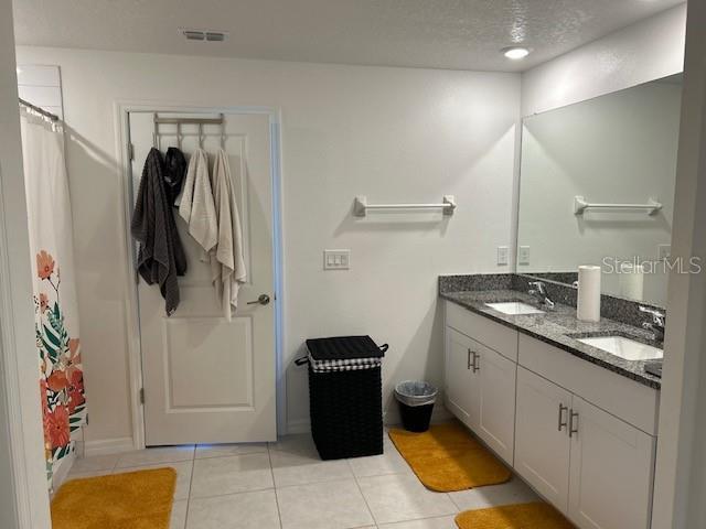 bathroom with a shower with shower curtain, a textured ceiling, vanity, and tile patterned floors