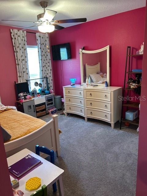 bedroom with ceiling fan and dark colored carpet