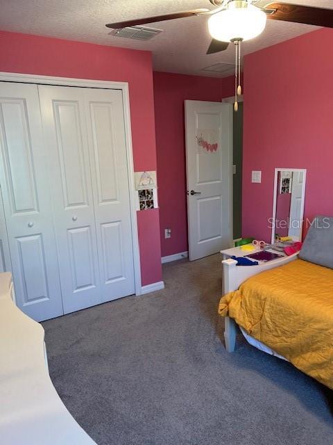 bedroom with ceiling fan, a closet, carpet, and a textured ceiling