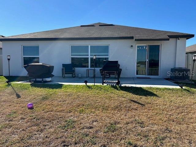 back of property with a patio, central AC unit, and a lawn