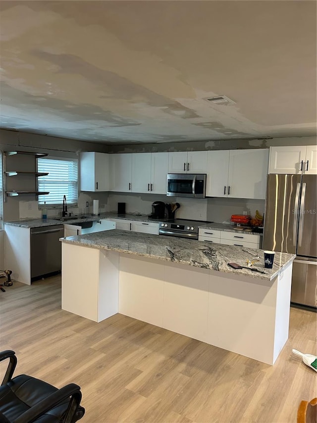 kitchen featuring white cabinets, light stone counters, and appliances with stainless steel finishes