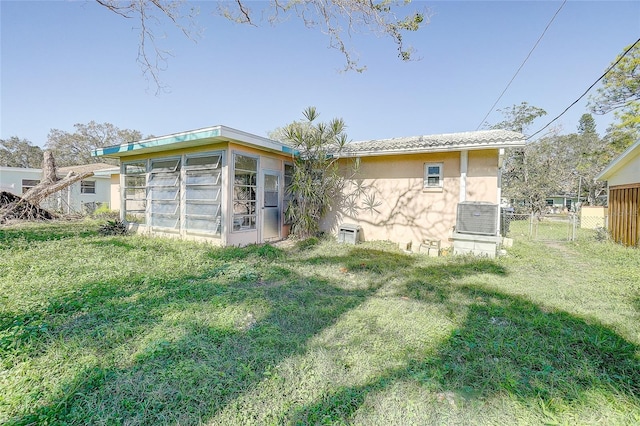 rear view of property with a yard and central AC unit