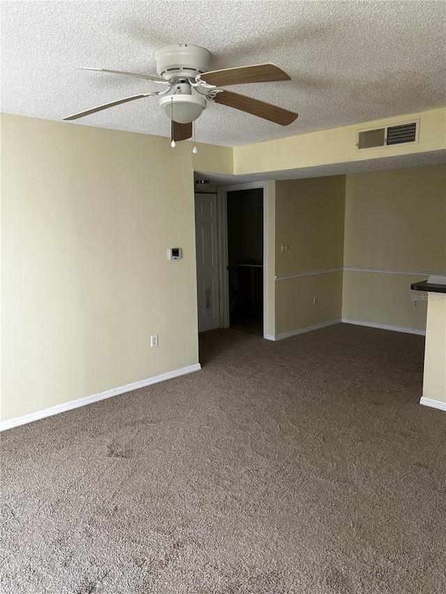 empty room with a textured ceiling, carpet floors, and ceiling fan