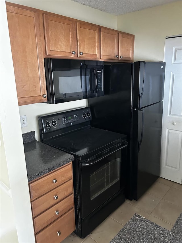 kitchen featuring black appliances, light tile patterned floors, and a textured ceiling