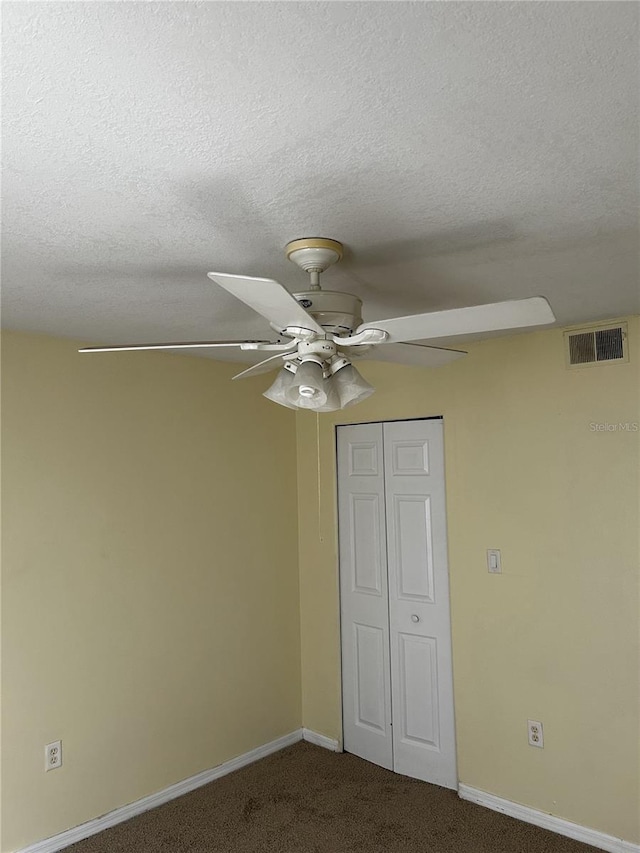 unfurnished bedroom featuring a textured ceiling, carpet floors, a closet, and ceiling fan