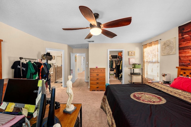 carpeted bedroom with ensuite bathroom, ceiling fan, a walk in closet, and a closet