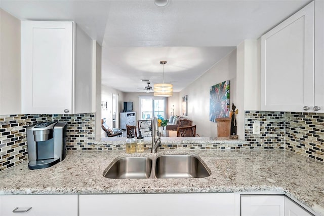 kitchen featuring ceiling fan, sink, light stone counters, backsplash, and white cabinets