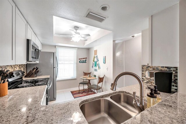 kitchen featuring white cabinets, stainless steel appliances, a raised ceiling, and sink