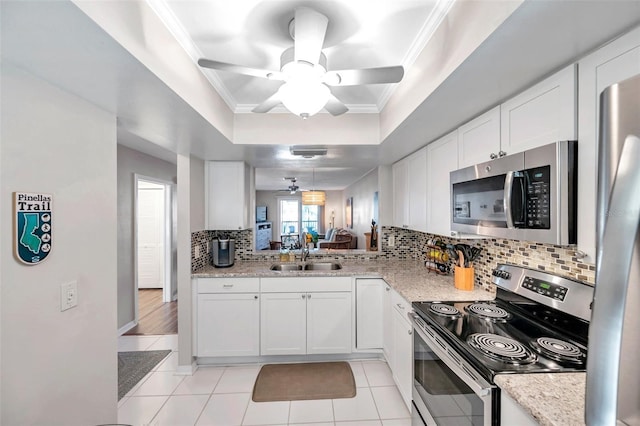 kitchen featuring decorative backsplash, stainless steel appliances, sink, light tile patterned floors, and white cabinets