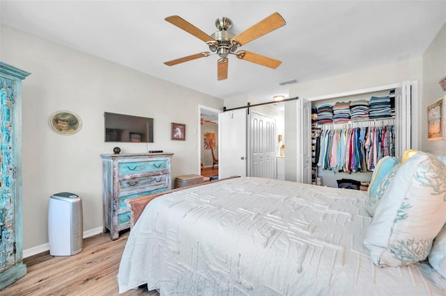 bedroom with ceiling fan, light hardwood / wood-style floors, and a barn door