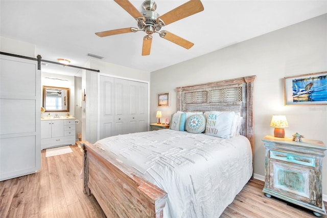 460 Paula Dr S Unit 101, Dunedin, FL 34698 - bedroom with light wood finished floors, a closet, a ceiling fan, and a barn door