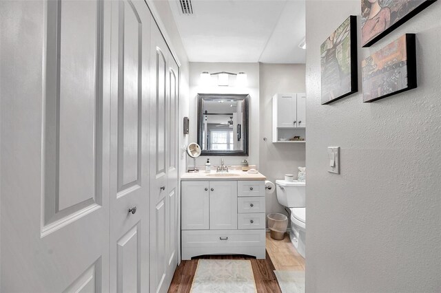 bathroom featuring vanity, wood-type flooring, and toilet