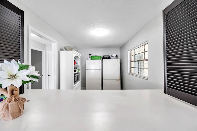 kitchen featuring white fridge, oven, and a textured ceiling