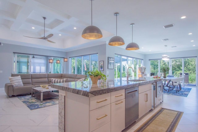 kitchen with coffered ceiling, a center island with sink, sink, hanging light fixtures, and stainless steel appliances