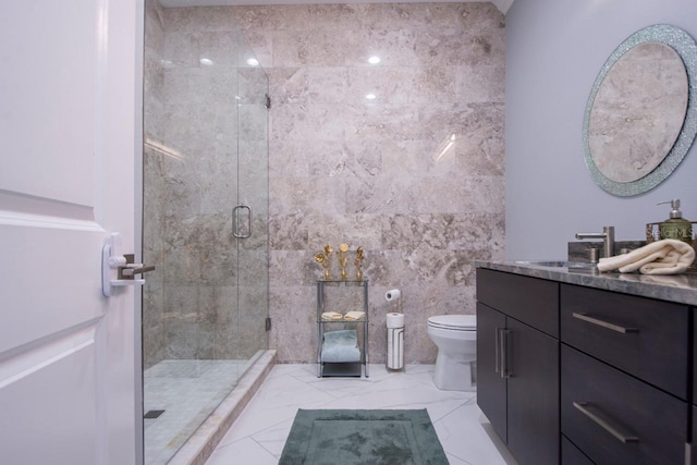 bathroom with a shower with door, vanity, tile walls, and toilet