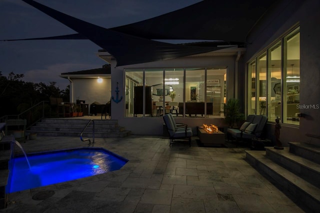 pool at twilight featuring pool water feature, an outdoor fire pit, and a patio