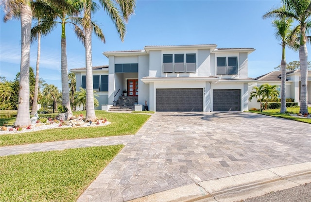 view of front of house with an attached garage, a front lawn, decorative driveway, and stucco siding