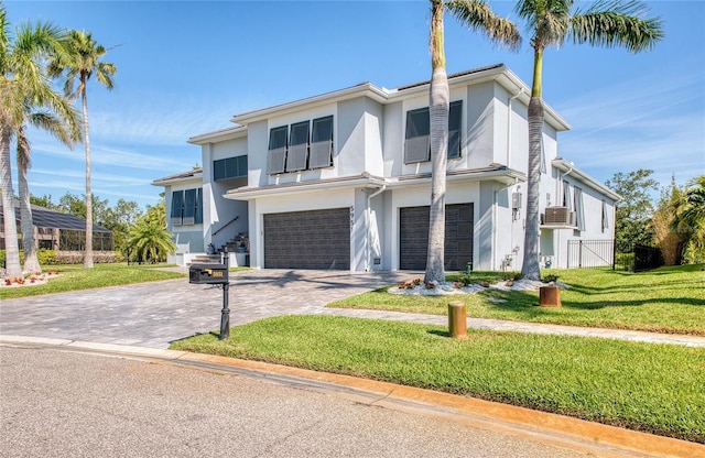 view of front of home featuring a garage, a front yard, decorative driveway, and stucco siding