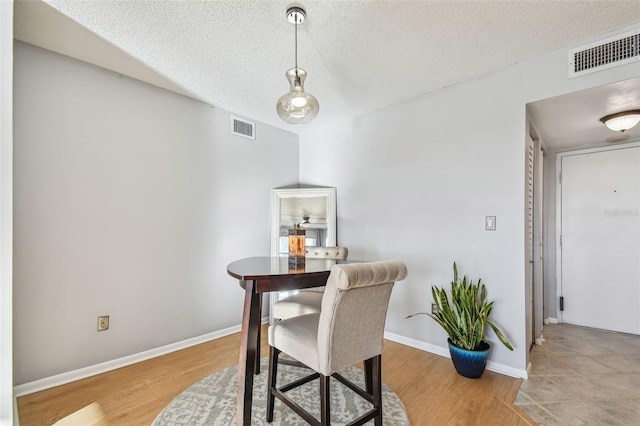 dining space with light hardwood / wood-style floors and a textured ceiling