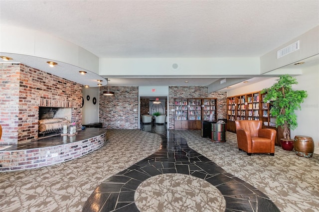 living room featuring a textured ceiling, a fireplace, and brick wall