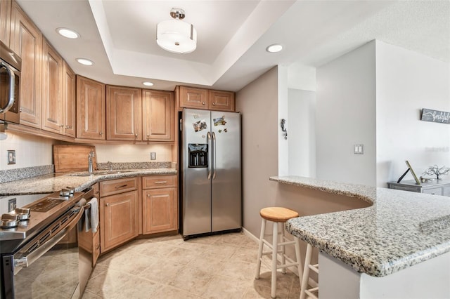 kitchen with light stone counters, a breakfast bar, stainless steel appliances, and sink