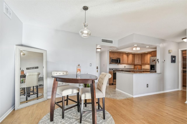 dining space with a textured ceiling and light wood-type flooring