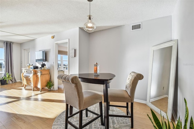 dining area featuring a textured ceiling, light hardwood / wood-style floors, and a wealth of natural light