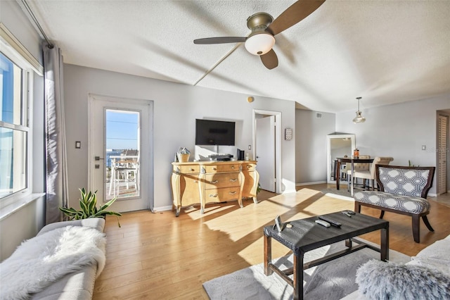 living room featuring a textured ceiling, light hardwood / wood-style flooring, and ceiling fan