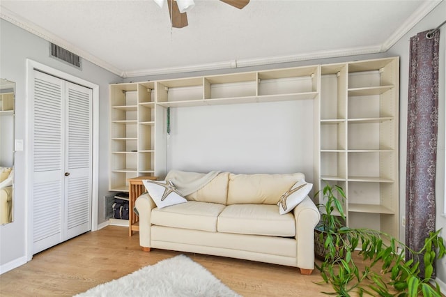 living area featuring hardwood / wood-style floors, ceiling fan, and ornamental molding