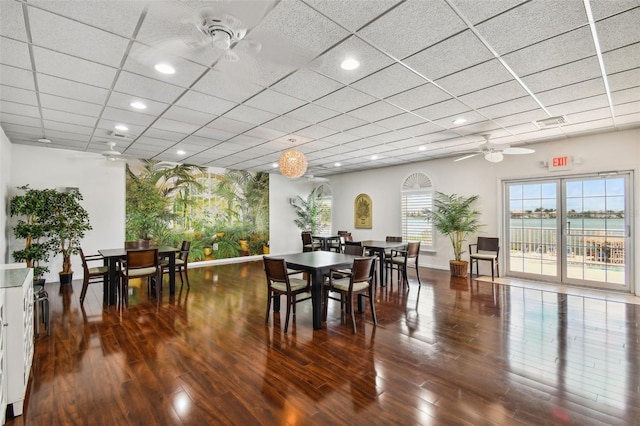 dining space featuring a paneled ceiling, hardwood / wood-style flooring, ceiling fan, and a water view