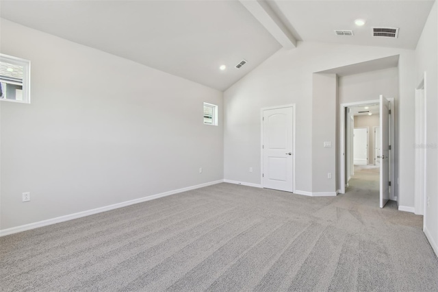 interior space with light carpet and vaulted ceiling with beams