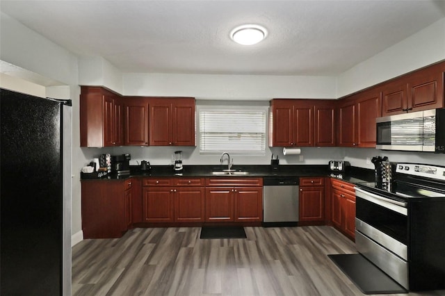 kitchen with sink, dark wood-type flooring, a textured ceiling, and appliances with stainless steel finishes