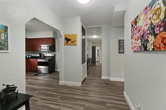 corridor with dark hardwood / wood-style flooring and a textured ceiling