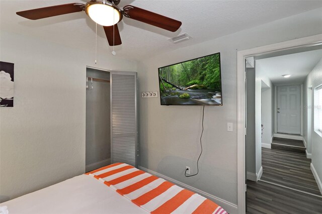 bedroom with a textured ceiling, dark hardwood / wood-style flooring, a closet, and ceiling fan