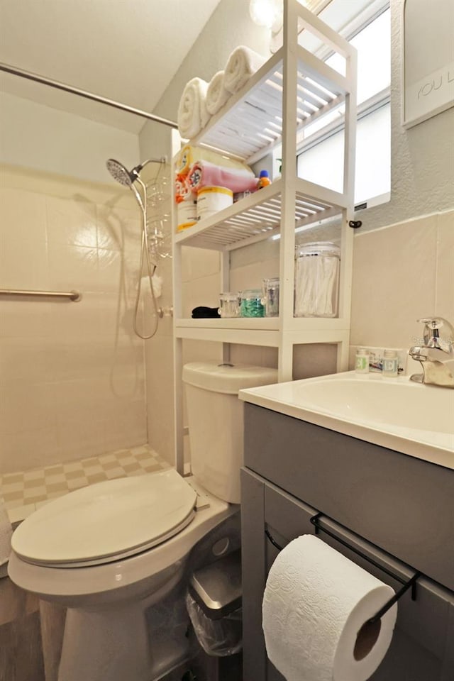 bathroom featuring a tile shower, toilet, vanity, and hardwood / wood-style flooring