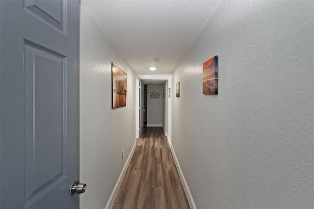 hallway featuring a textured ceiling and dark hardwood / wood-style floors