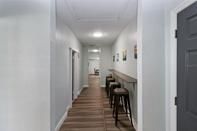 hall with a textured ceiling and dark wood-type flooring