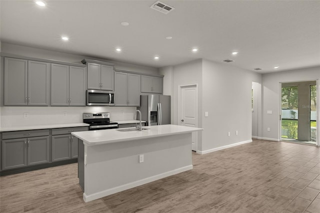 kitchen featuring gray cabinets, a center island with sink, stainless steel appliances, and sink