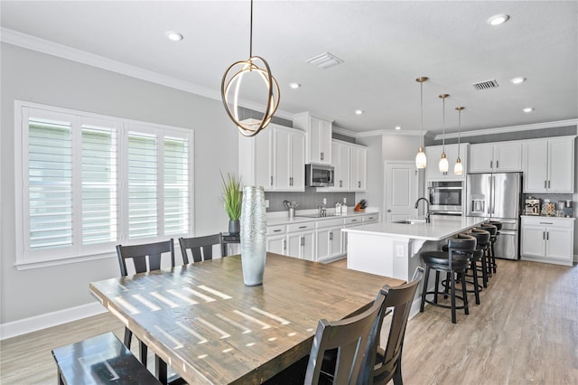 dining area with light hardwood / wood-style floors, ornamental molding, and sink