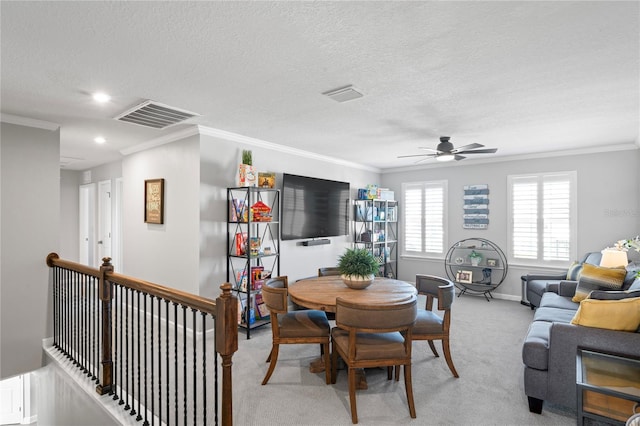 carpeted dining space with ceiling fan, ornamental molding, and a textured ceiling