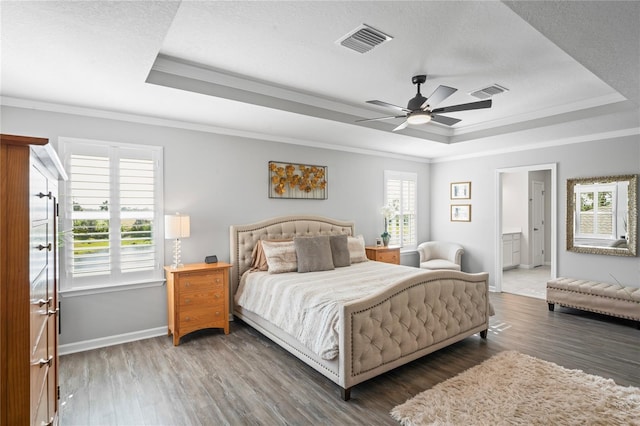 bedroom featuring dark hardwood / wood-style flooring, a tray ceiling, multiple windows, and ceiling fan