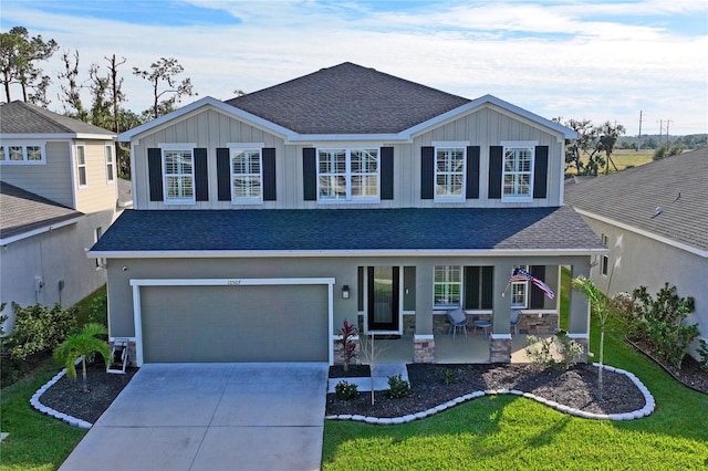 view of front of house with covered porch, a garage, and a front yard