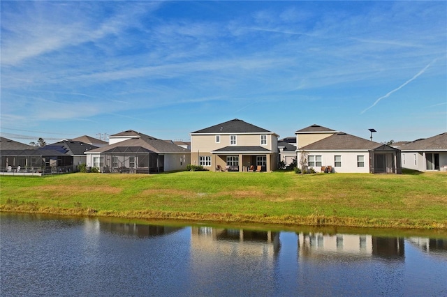 back of property featuring a lanai, a lawn, and a water view