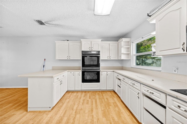 kitchen featuring white cabinets, light hardwood / wood-style floors, a textured ceiling, and double oven