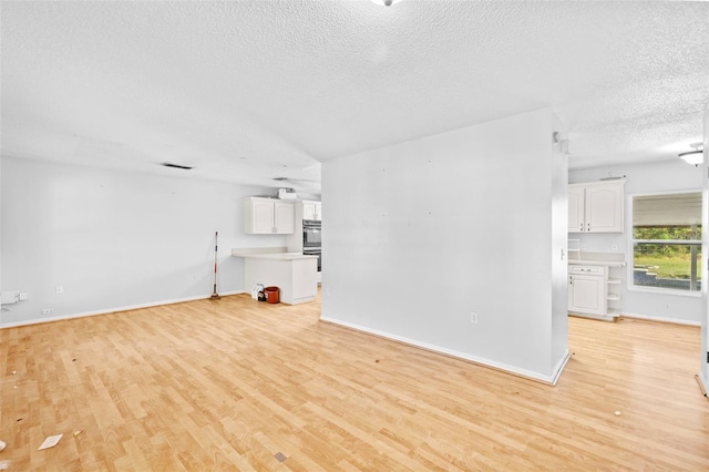 unfurnished living room featuring light hardwood / wood-style floors and a textured ceiling